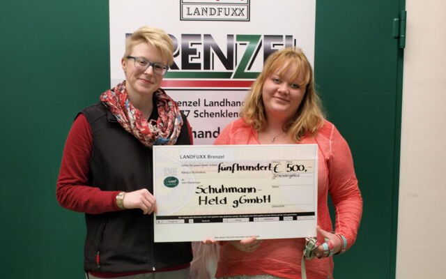 Marktleiterin Meike Thomas (l.) übereicht den Spendenscheck an Kristin Karger vom Projekt Therapiebegleithund mit Hündin Amy